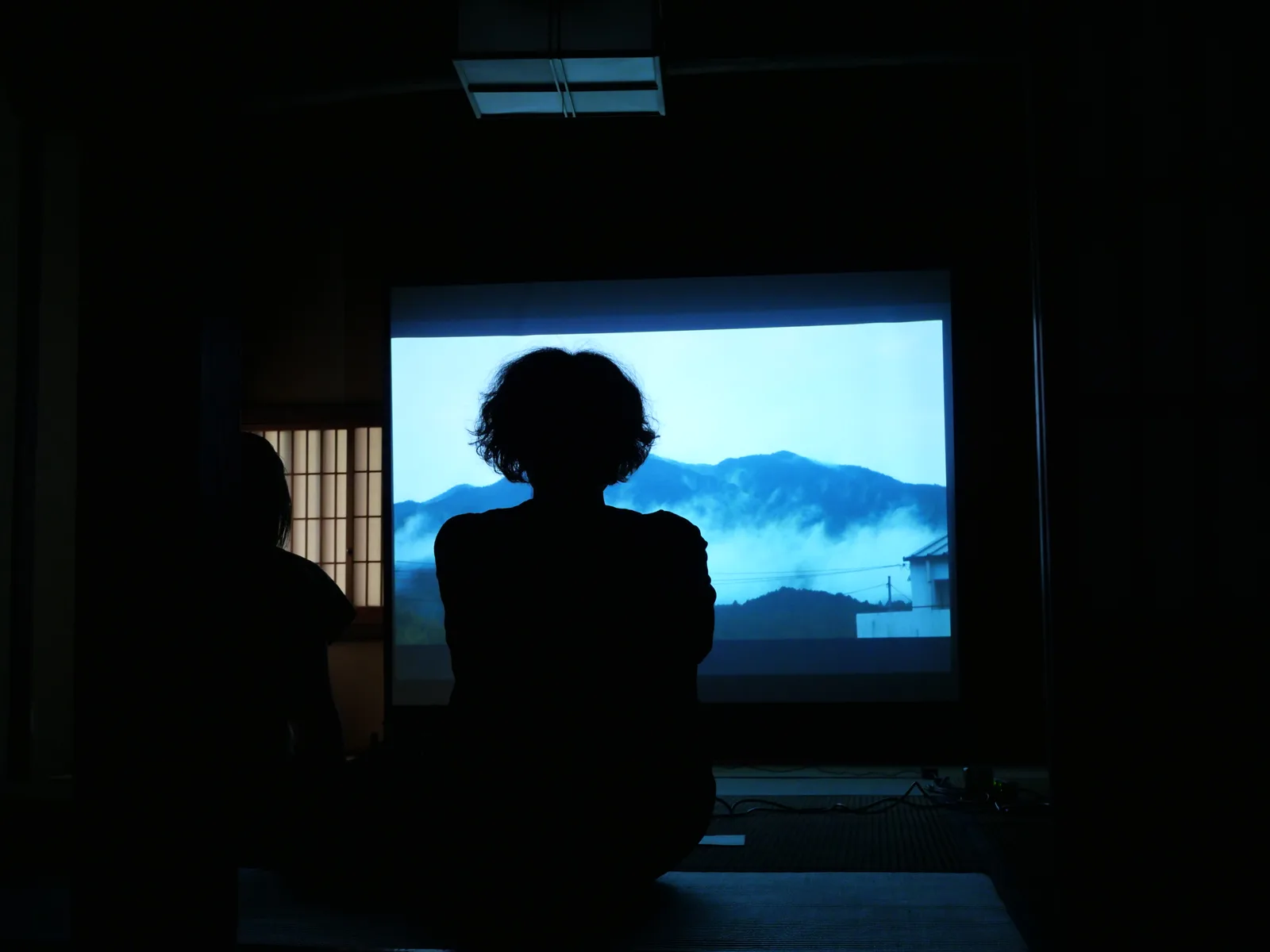 秋月の会場で、スクリーンに映る映像を鑑賞する人々。過去の開催風景